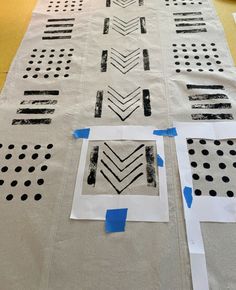 several pieces of paper are taped together to make a table runner with black and white designs