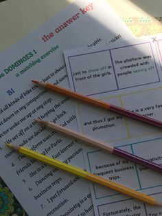 three pencils are sitting on top of two sheets of paper with words and pictures