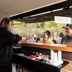 a woman is handing something to a man at an outdoor bar