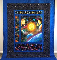 a quilted wall hanging with an image of planets and the sun in space on it