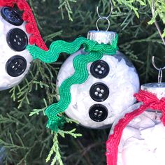 two snowman ornaments are hanging from a christmas tree with green and red yarn on them