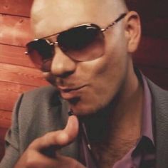 a bald man wearing sunglasses and pointing to the side with his finger in front of him