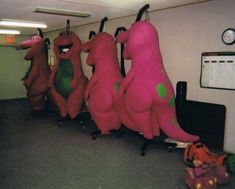 several stuffed animals are lined up in an office cubicle, one is pink and the other is green