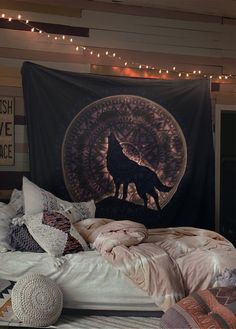 a bed room with a large tapestry on the wall next to it and some pillows