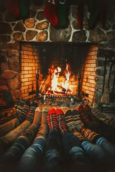 there are many pairs of socks sitting in front of the fireplace with their feet up