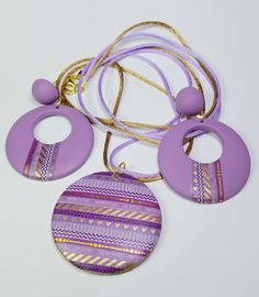 three pieces of purple and gold jewelry on a white surface with two circular pendants