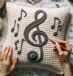 a woman is working on a pillow with musical notes