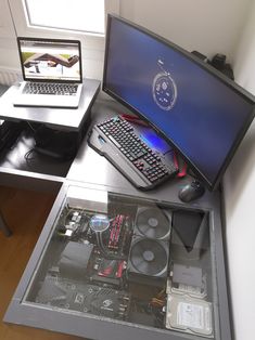 a laptop computer sitting on top of a glass table next to a desktop computer monitor