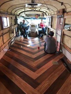 two men sitting in the back of a truck with wood flooring on it's sides