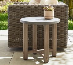 a wicker chair sitting next to a table with a potted plant on it