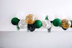 the balloons are decorated with leopard print and green palm leaves, along with white balls