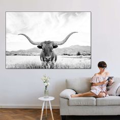 a woman sitting on a couch in front of a wall with a cow's head