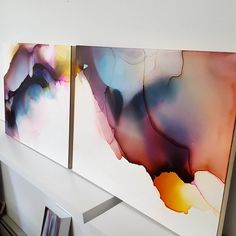 two abstract paintings are hanging on the wall