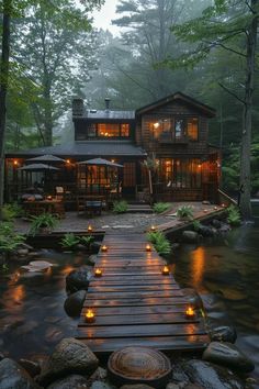 a cabin in the woods is lit up at night with candles on the walkway leading to it