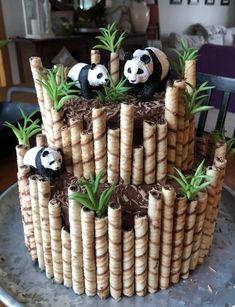 a cake made to look like bamboo sticks with pandas on top and plants in the middle