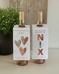 two bottles of wine sitting on top of a table next to a potted plant