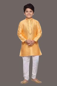 a young boy in a yellow outfit standing with his hands on his hips and wearing white pants