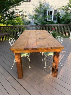 a wooden table sitting on top of a wooden deck next to a white metal chair