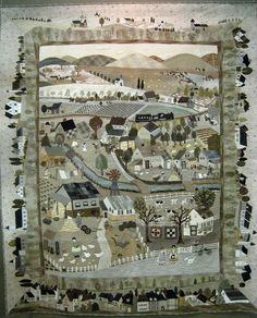 a quilted wall hanging with houses and trees on it's sides, in front of a white fence