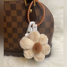 a teddy bear is attached to a brown and tan purse with a flower on it