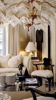 a living room filled with furniture and a chandelier hanging over the top of it