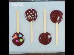 four chocolate covered lollipops are on sticks