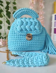 a crocheted blue purse sitting on top of a table next to a chain