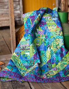 a blue and green blanket sitting on top of a wooden floor next to a potted plant