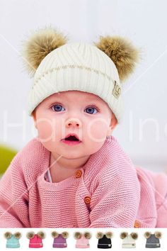 a baby wearing a hat with two pompoms