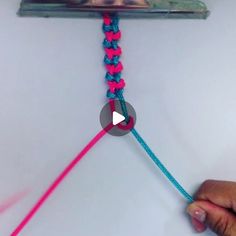 someone is pulling the end of a crochet hook together with pink and blue yarn