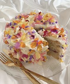 a cake with white frosting and colorful flowers on it next to a gold fork