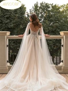 a woman in a wedding dress standing on a balcony with her back to the camera