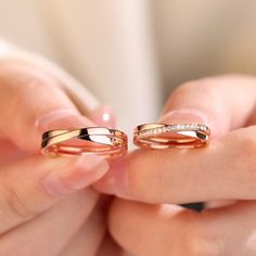 two women's hands holding gold wedding rings with diamonds on each one and the other hand