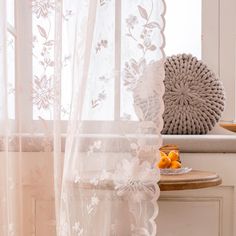 a window with sheer curtains and fruit on the table