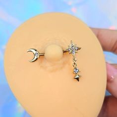 a person is holding an object with a cross and moon charm on it's end