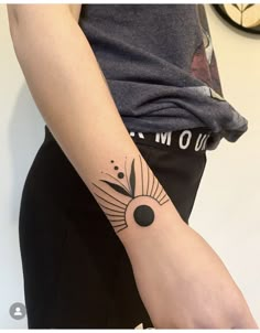 a woman's arm with a tattoo on it and a clock in the background