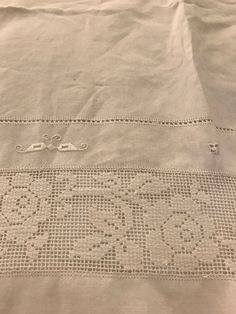 an embroidered sheet with two scissors on it and some holes in the fabric that have been stitched together