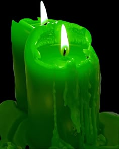 two green candles with one lit and the other turned on, in front of a black background