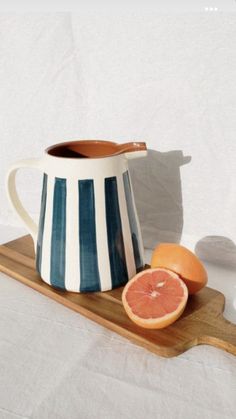 a striped pitcher and grapefruit on a cutting board