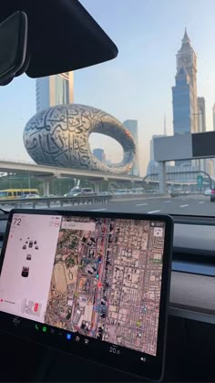 a laptop computer sitting on the dashboard of a car in front of a cityscape