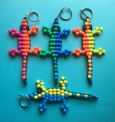 three key chains made out of beads with different colors and shapes in the shape of a lizard