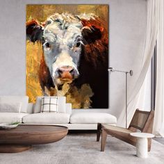 a painting of a cow is hanging in a living room with white couches and chairs