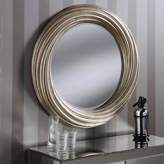 a round mirror sitting on top of a dresser next to a vase and faucet