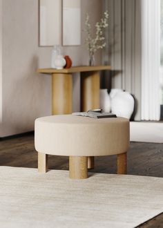 a round ottoman sitting on top of a white rug in a living room next to a table