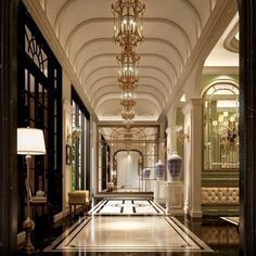 an elegant hallway with chandelier and marble flooring is pictured in this image