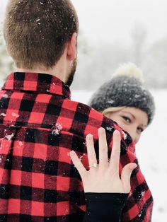 a man and woman standing in the snow with their hands on each other's shoulders