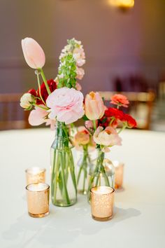 vases filled with flowers sitting on top of a table next to candles and glasses