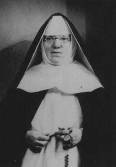 an old black and white photo of a nun holding something in her hands with both hands