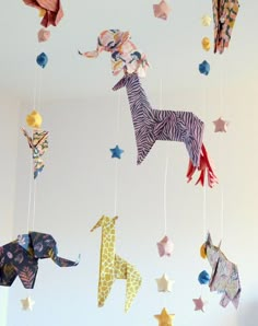 some paper animals are hanging from strings in the air with star decorations on top of them