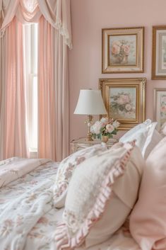 a bedroom with pink walls and pictures on the wall above the bed, along with a lamp